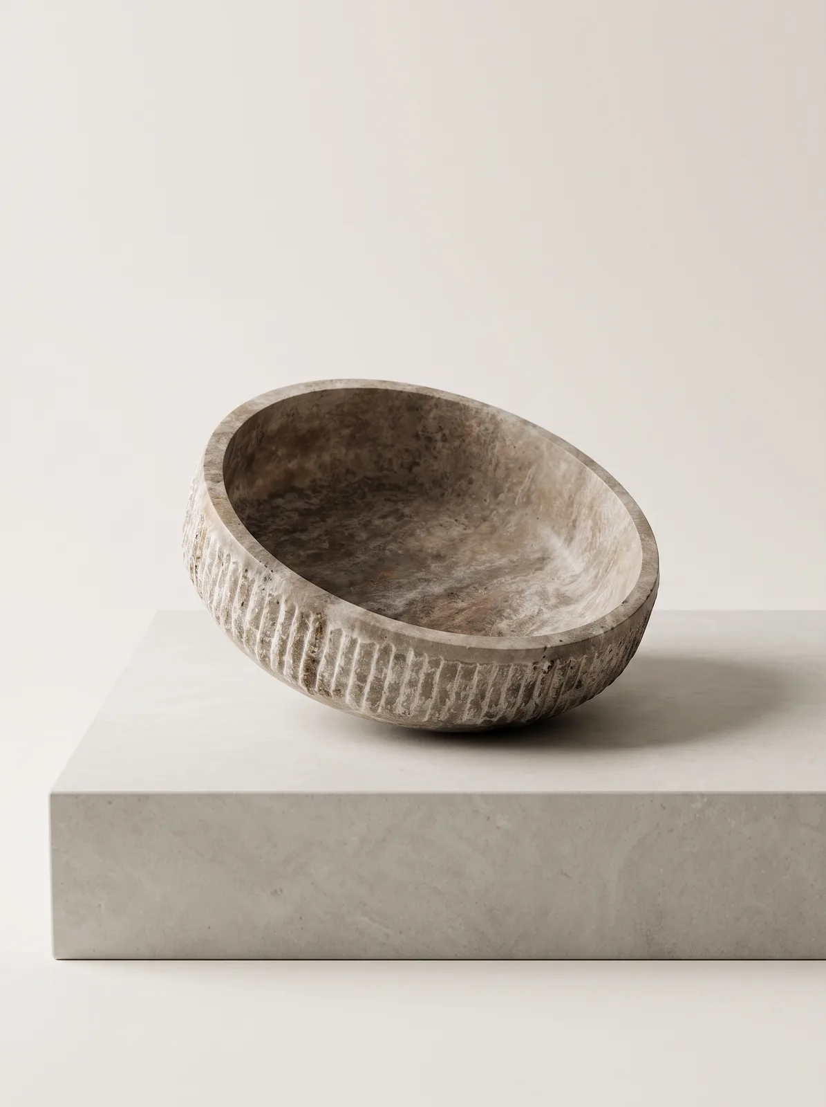 Rustic serving bowl carved from silver travertine on a neutral background